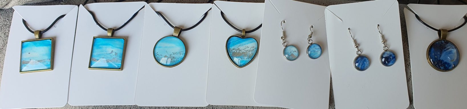 Square, round and heart shaped pendants, drop earrings containing pieces of the original light blue alcohol ink &silver gilded "Open skies"