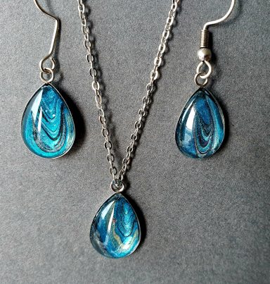 Stainless steel tear drop pendant and earrings containing parts of original art in turquoise, silver and black.