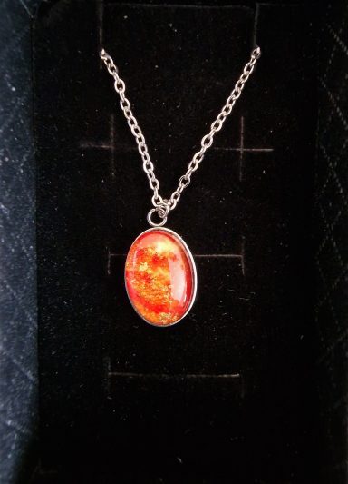 Stainless steel oval pendant containing vivid orange yellow artwork