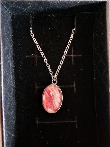 Stainless steel oval pendant containing parts of original art in  pearl and pink with hint of bronze shimmer.