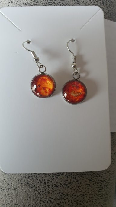 Silver colour round drop earrings containing ontaining firery red and orange original art work