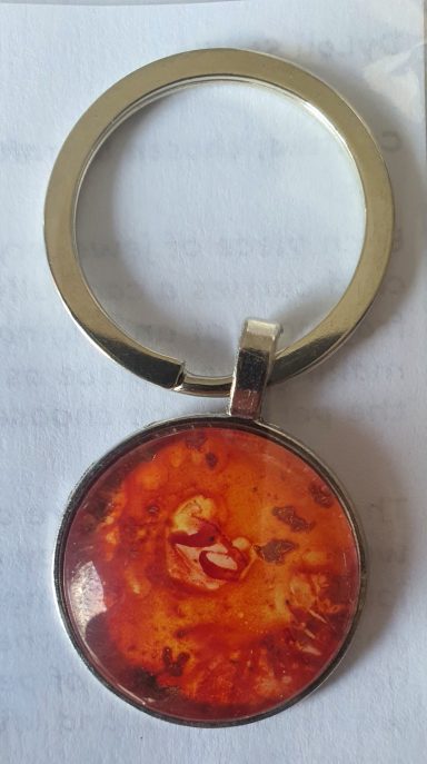 Silver round keyring containing firery red and orange original art work