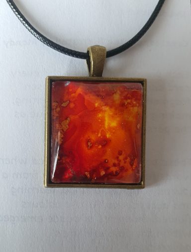 Square bronzed pendant containing firery red and orange original art work