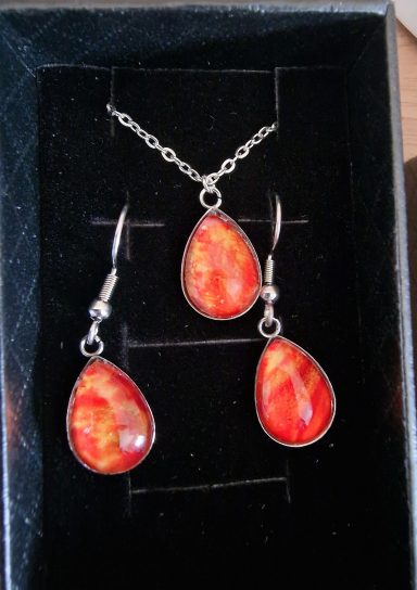 Stainless steel tear drop earrings and pendant containing vivid orange yellow artwork