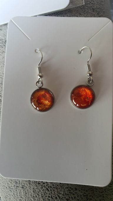Silver colour round drop earrings containing ontaining firery red and orange original art work