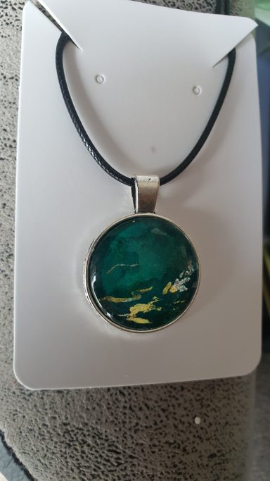 Silver round pendant containing containing dark green and gold gilded original art work